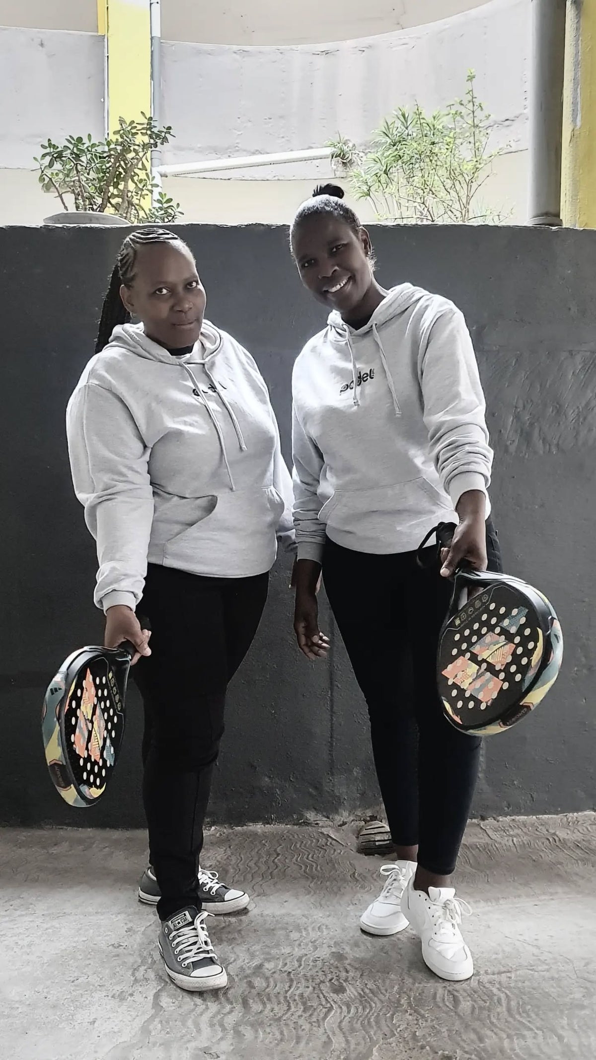 Two padel players wearing Zazu hoodies and holding rackets
